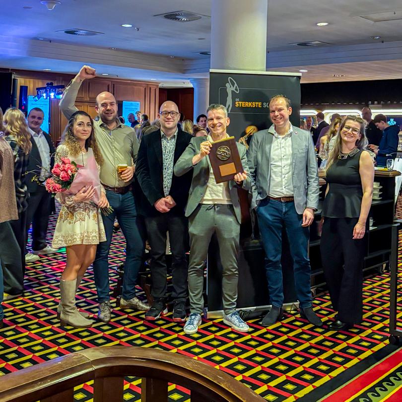 Groep PWA-medewerkers poseert op de uitreiking van de Sterkste Schakel en houdt trots de sectorprijs dienstverlening groot vast.