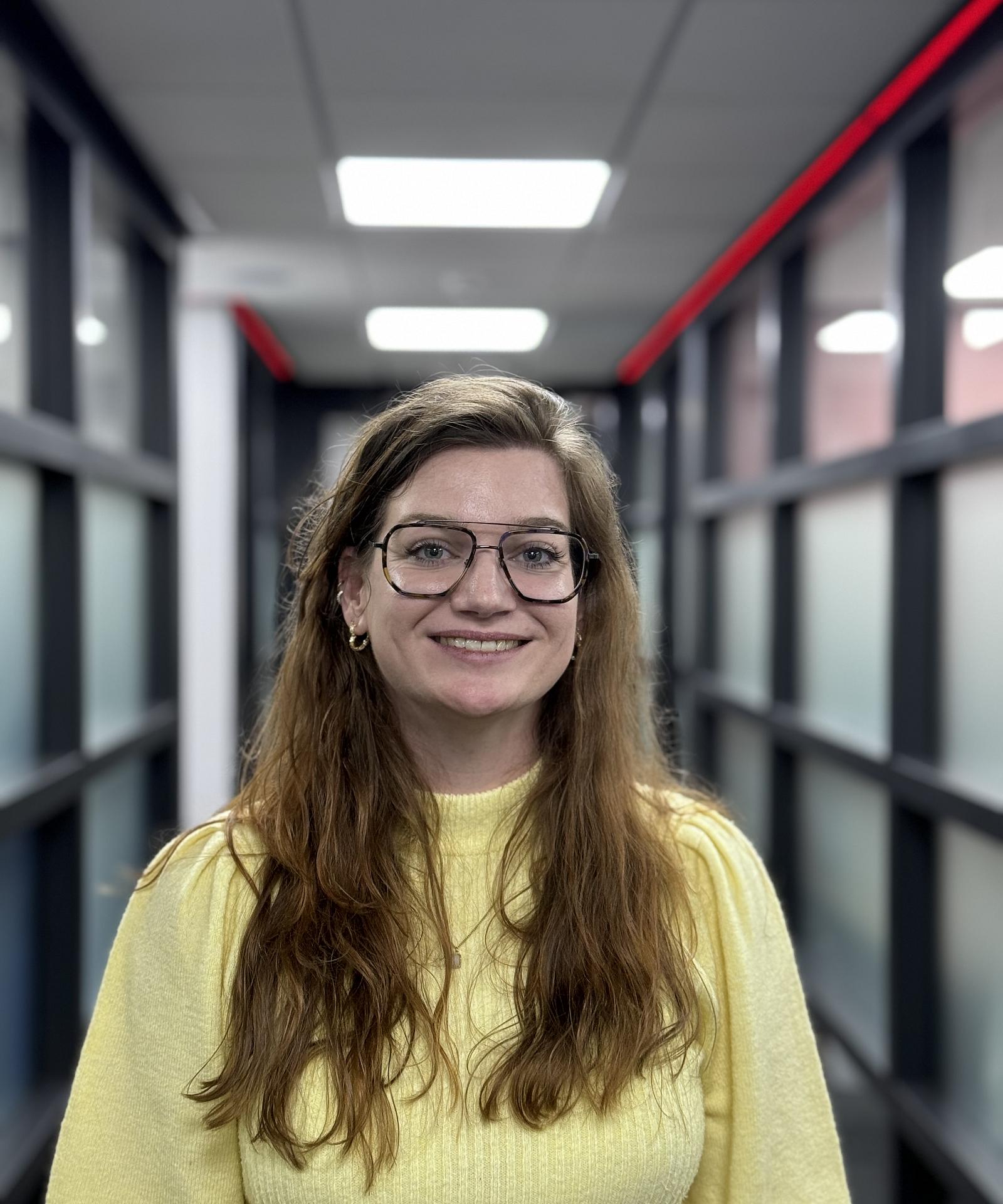 Lachende vrouw in gang van een kantooromgeving.