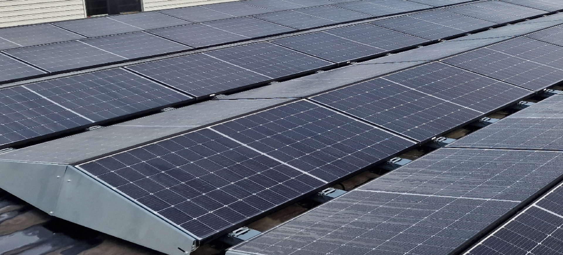 Rijen zonnepanelen gemonteerd op een plat dak van een bedrijfsgebouw, opgesteld in metalen frames voor optimale zonne-energieopwekking.