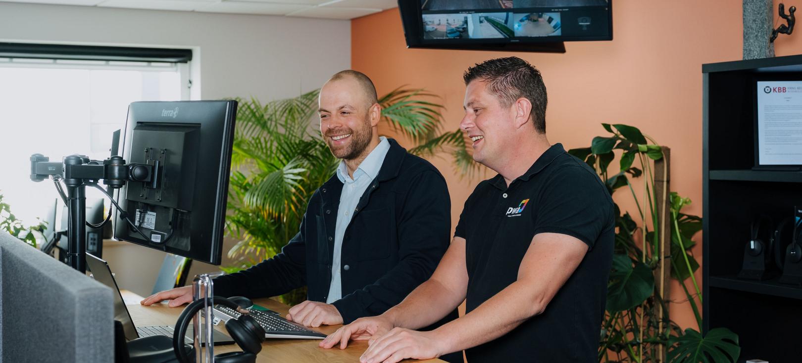 Twee PWA-medewerkers achter een computer in een kantooromgeving.