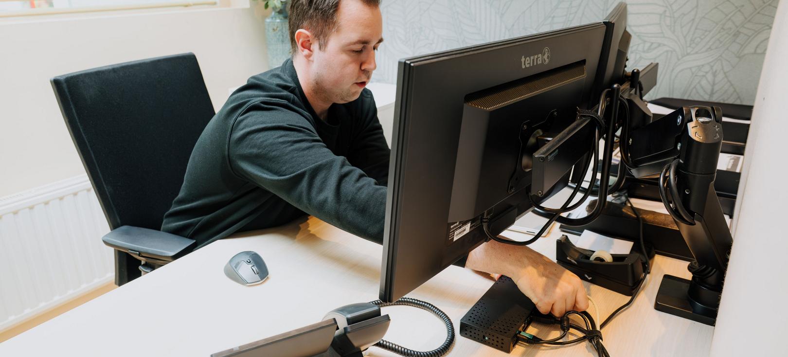 PWA-medewerker werkt aan de bekabeling van een computerwerkplek.