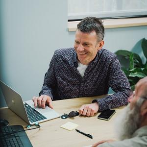 Overleg tussen collega’s aan tafel waarbij samen wordt gewerkt op een laptop in een informele setting.