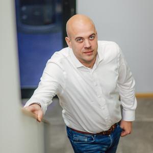 Man in witte blouse die een trap oploopt in een kantooromgeving, met een serverruimte zichtbaar op de achtergrond.