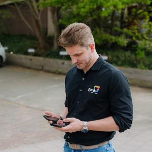 IT-consultant van PWA gebruikt zakelijke mobiele communicatie tijdens werkzaamheden op locatie.