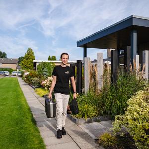 IT-specialist loopt met koffer in hand op een vakantiepark in een groene omgeving