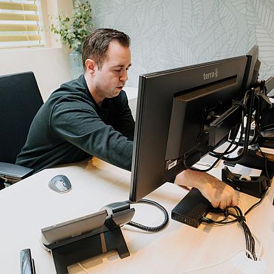 PWA-medewerker werkt aan de bekabeling van een computerwerkplek.