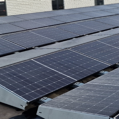 Rijen zonnepanelen gemonteerd op een plat dak van een bedrijfsgebouw, opgesteld in metalen frames voor optimale zonne-energieopwekking.