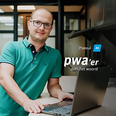 Man van PWA staat achter een bureau met laptop op kantoor tijdens de rubriek PWA’er aan het woord.