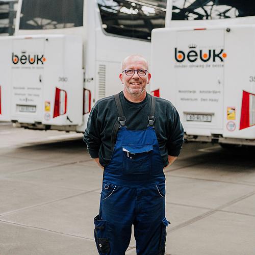 Monteur in werkkleding voor Beuk touringcars op bedrijfsterrein