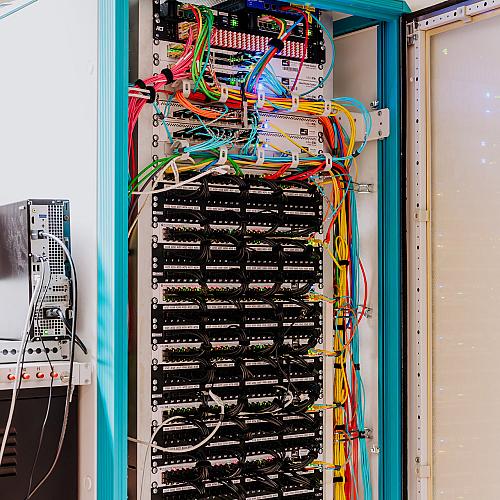 Serverkast vol nette, kleurrijke datakabels en apparatuur die de IT-infrastructuur van het bedrijf ondersteunt.