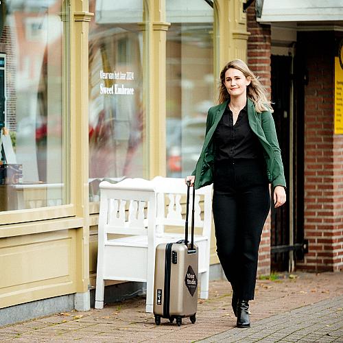 Medewerkster van Van Kesteren loopt langs een winkelpand met een rolkoffer in de hand.