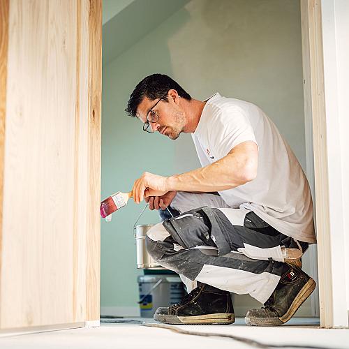 Schilder van Van Kesteren werkt geconcentreerd aan houtwerk tijdens een binnenproject.