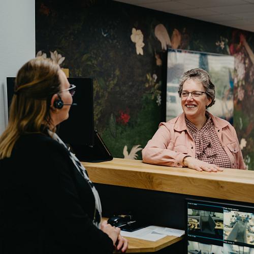 PWA-collega’s in gesprek bij de balie terwijl zij samenwerken aan ondersteuning en klantvragen.