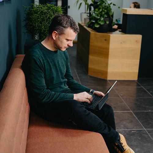 PWA-medewerker werkt geconcentreerd op een laptop in de ontvangstruimte van het kantoor.