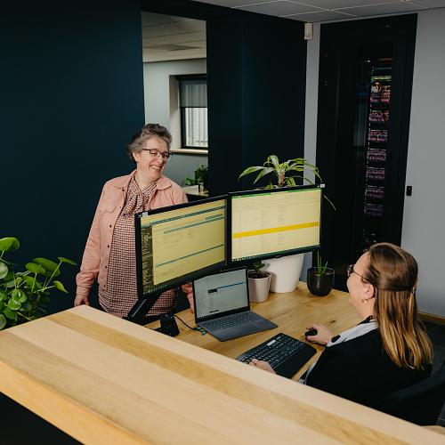 Collega’s van PWA werken samen aan de servicedesk met meerdere schermen en zicht op systemen.
