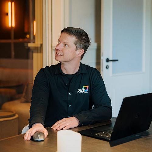 PWA-medewerker werkt met een laptop bij een klant op locatie voor IT-beheer en ondersteuning.