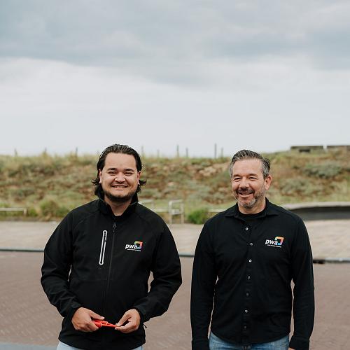 Twee PWA-medewerkers staan buiten bij een klant op locatie tijdens een bezoek voor IT-beheer.