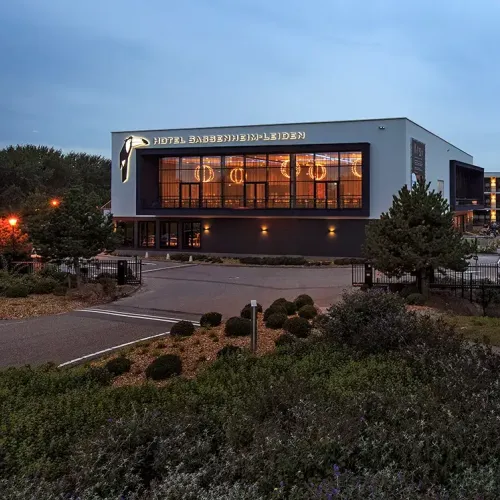 Medewerker van PWA ontvangt een bezoeker bij de receptie, in een warme en gastvrije kantooromgeving met natuurlijke accenten.