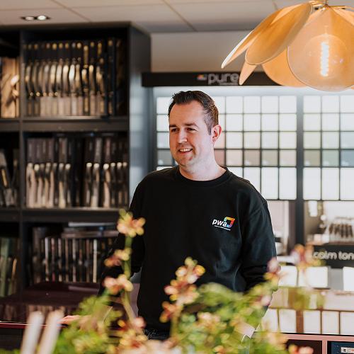 PWA-medewerker in gesprek met een klant in een inspirerende showroomomgeving.