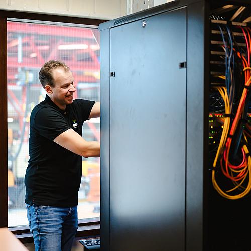 man met zwart shirt die kabels in een patchkast prikt