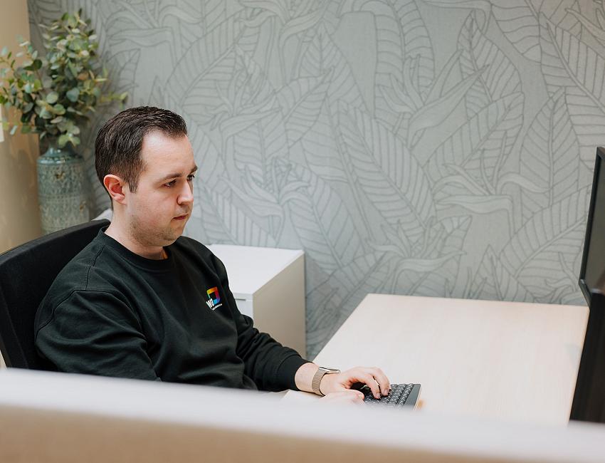 IT-specialist van PWA werkt aan een beheer- en ondersteuningsvraag achter zijn werkplek.