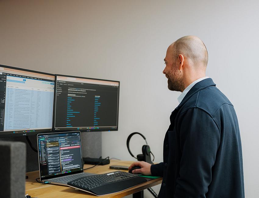 IT-specialist van PWA monitort en beheert klantomgevingen vanaf een werkplek met meerdere schermen.