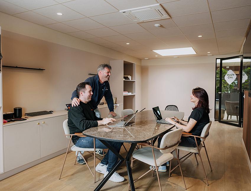 PWA-medewerkers overleggen met een klant aan tafel met laptops tijdens een IT-bezoek op locatie.