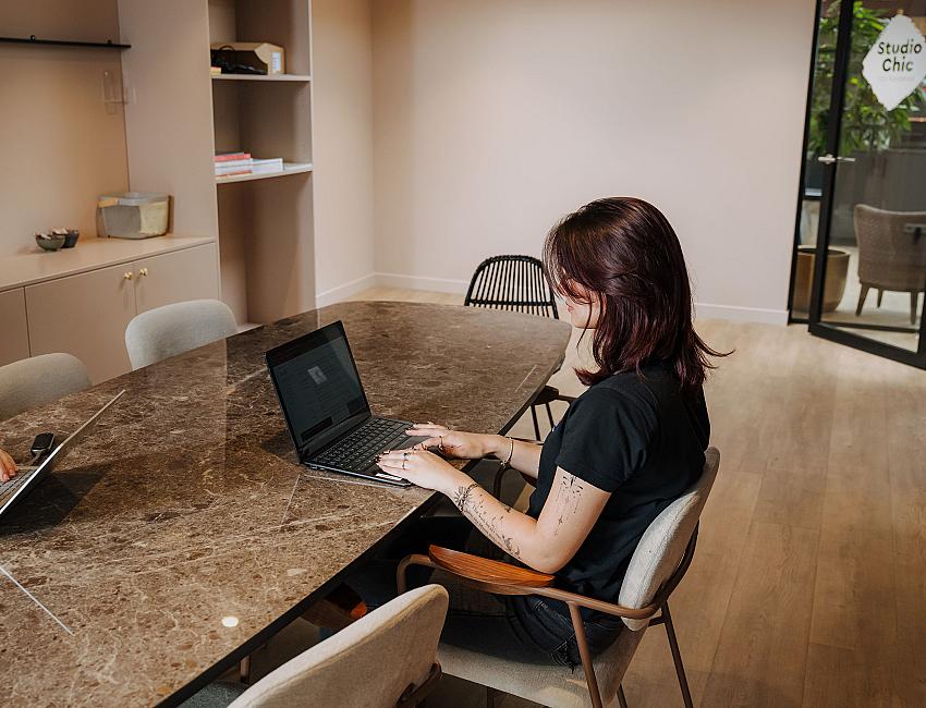 PWA-medewerker werkt op een laptop tijdens een overleg in een vergaderruimte.