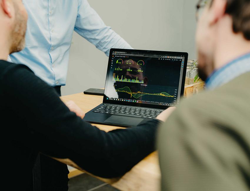 Medewerkers van PWA bekijken samen technische data op een laptop, tijdens een overlegmoment op kantoor.