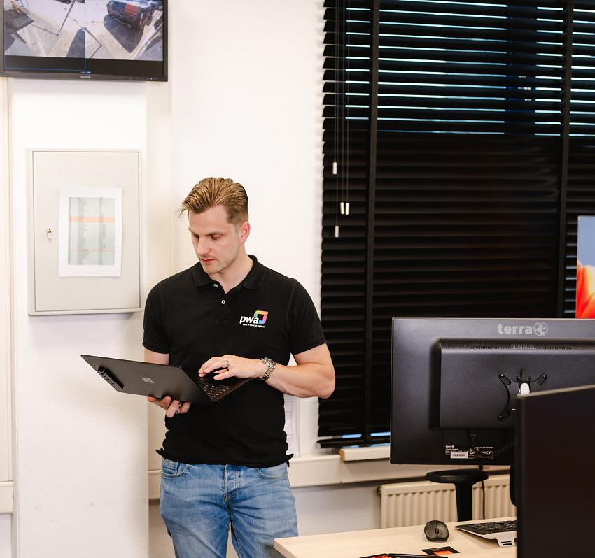 Collega staat in de deuropening van zijn auto met een PWA logo op de deur